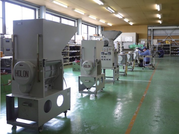 工場内に並ぶ組み立て途中の粉砕機。奥では従業員が作業している