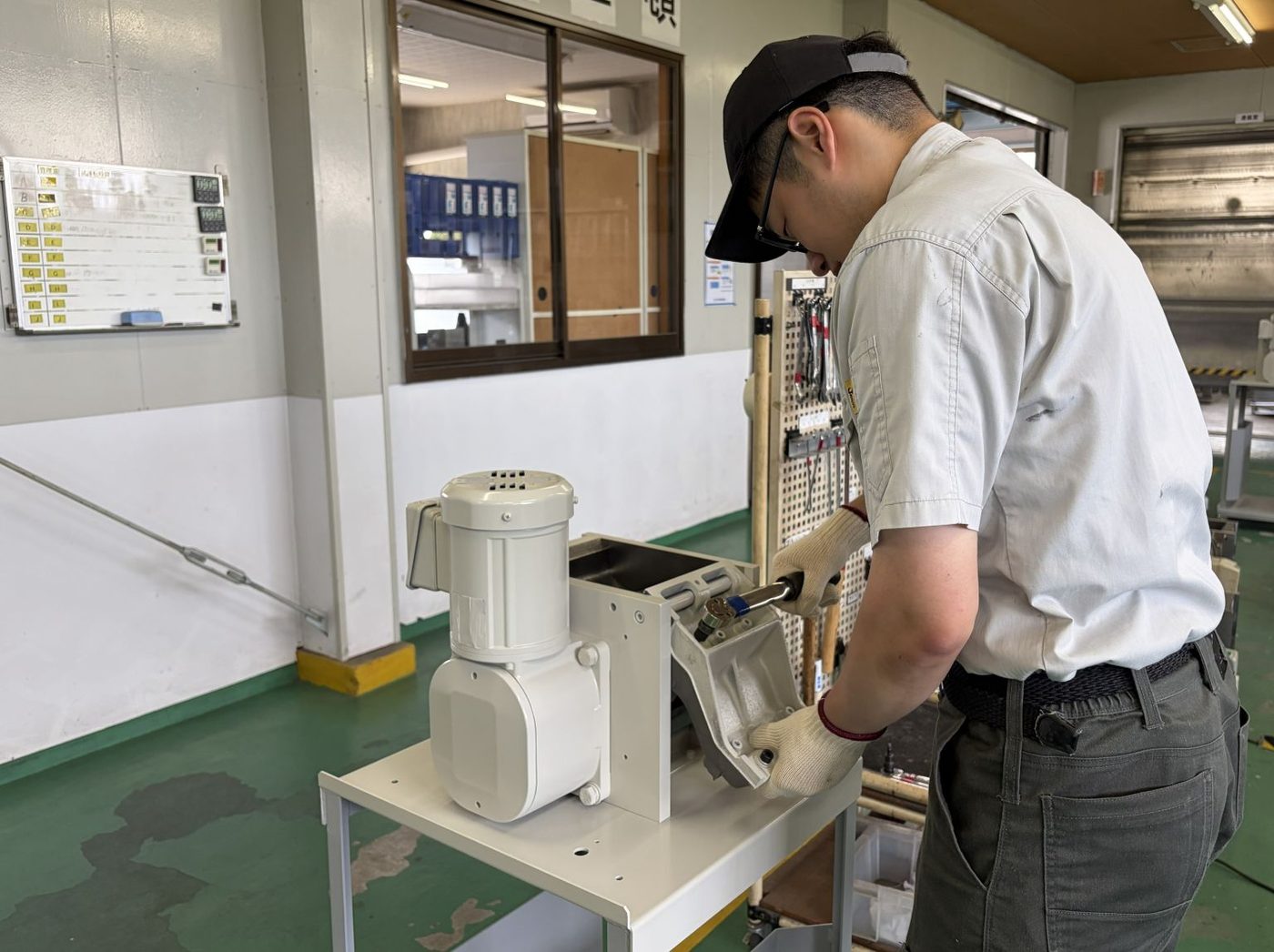 作業台で製品の組み立てと配線を行う従業員